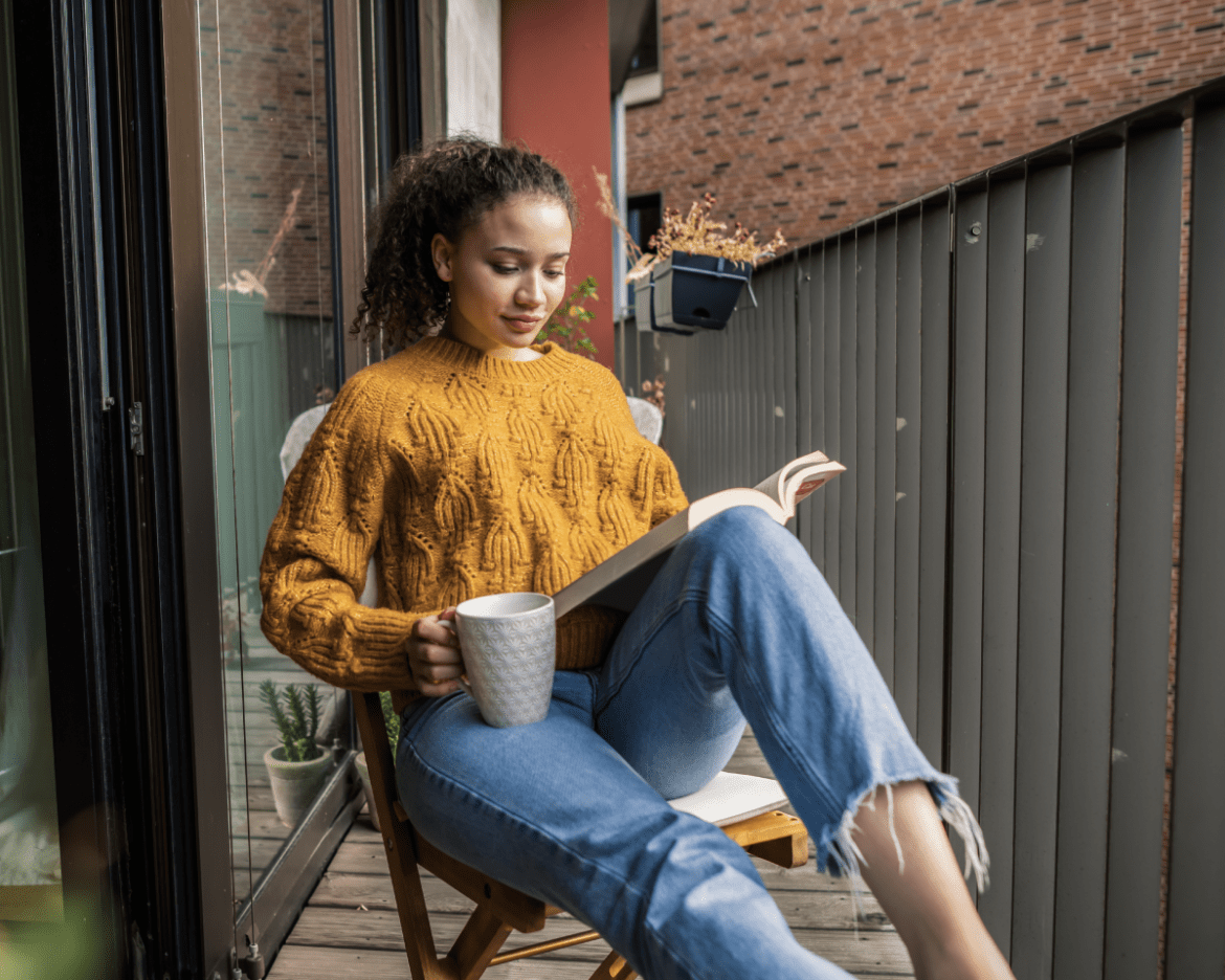 Mujer leyendo un libro en su balcón
